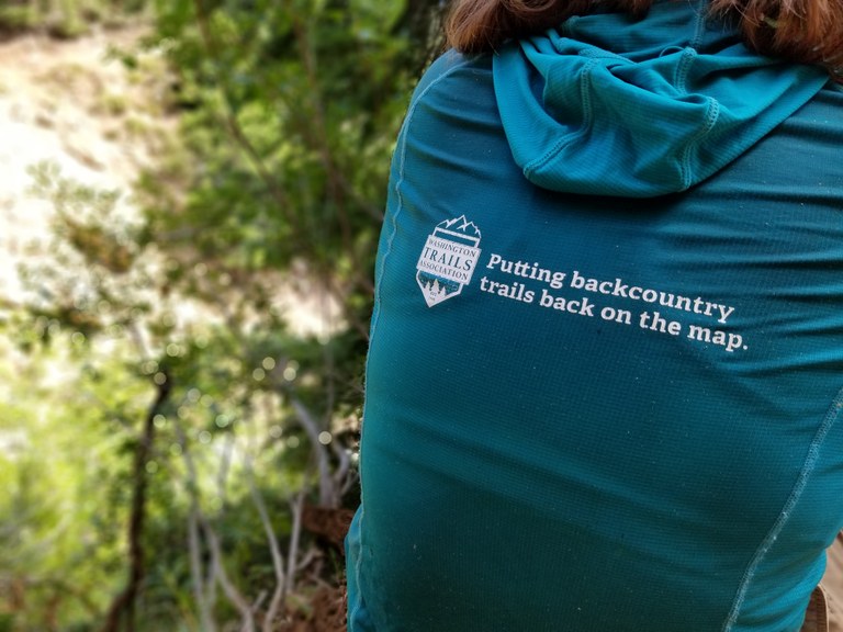 An LTF crew member with a shirt saying "putting backcountry trails back on the map".