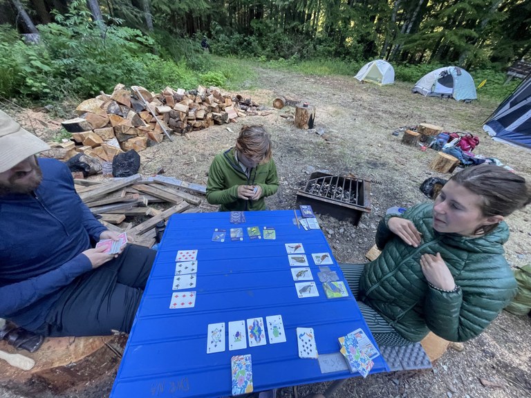 Three LTF crew members play cards at a table in the backcountry.