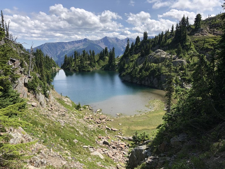 Looking down at a blue lake among rocky, tree spotted hillsides