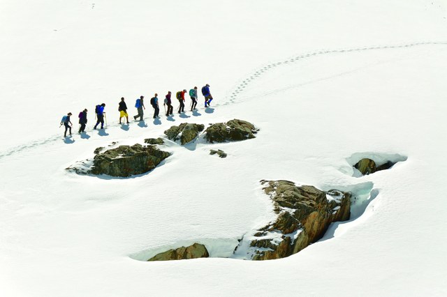 Lines, colors, shapes, textures and shadows all add to this photo of spring hikers on Pinnacle Peak in Mount Rainier National Park. The exposure maintains the white color of the snow but also shows texture and detail, adding overall interest to the photo. Photo by Doug Diekema.