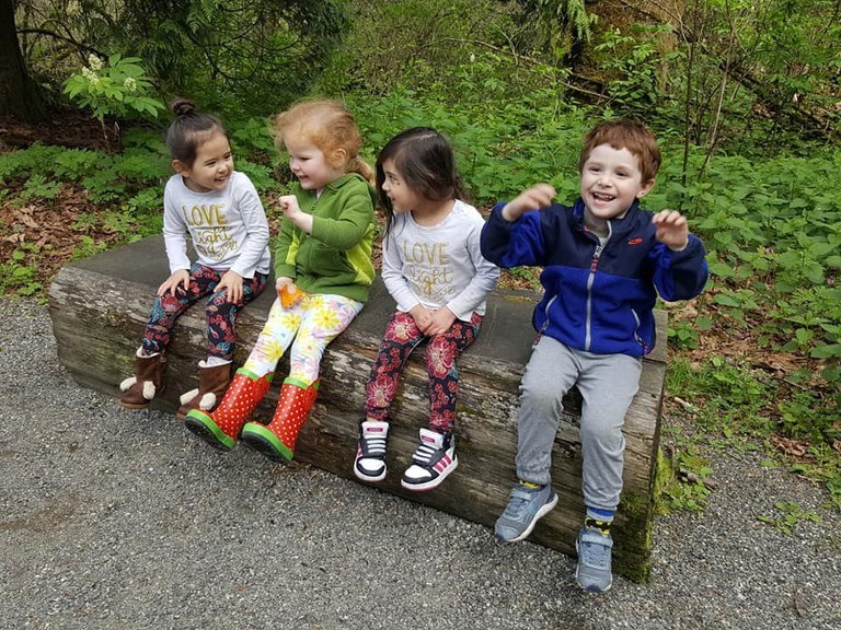 four kids sit on a log happily at the Brightwater Center.