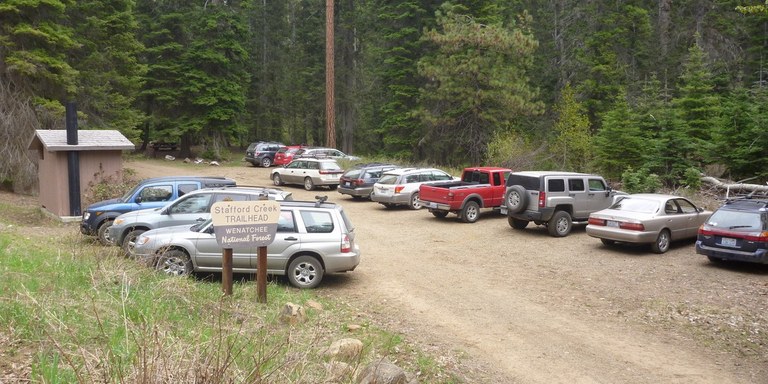 a dozen or so cars are parked neatly at a Forest Service trailhead