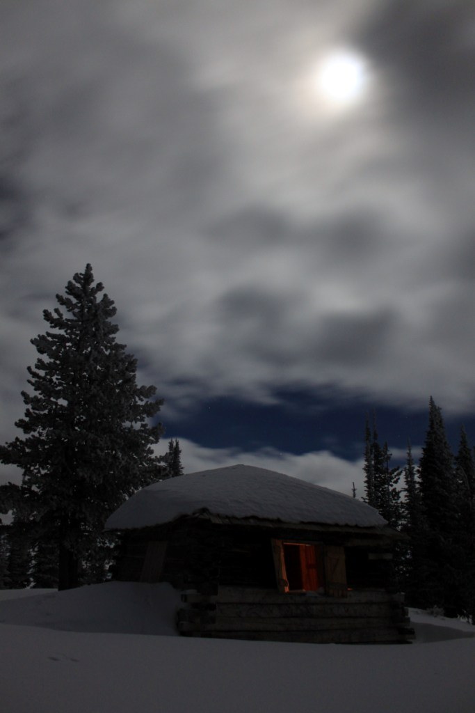 Columbia Mountain Lookout under the moon which is under the clouds.
